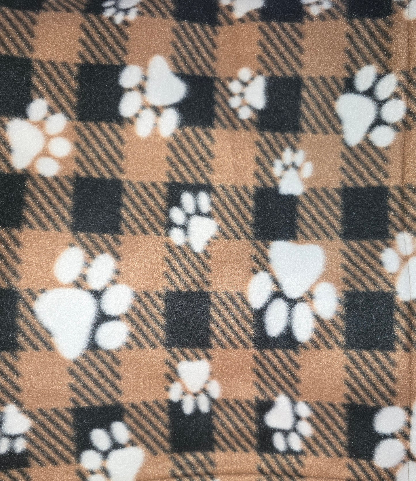 Black and brown plaid fleece dog blanket with white paw prints.