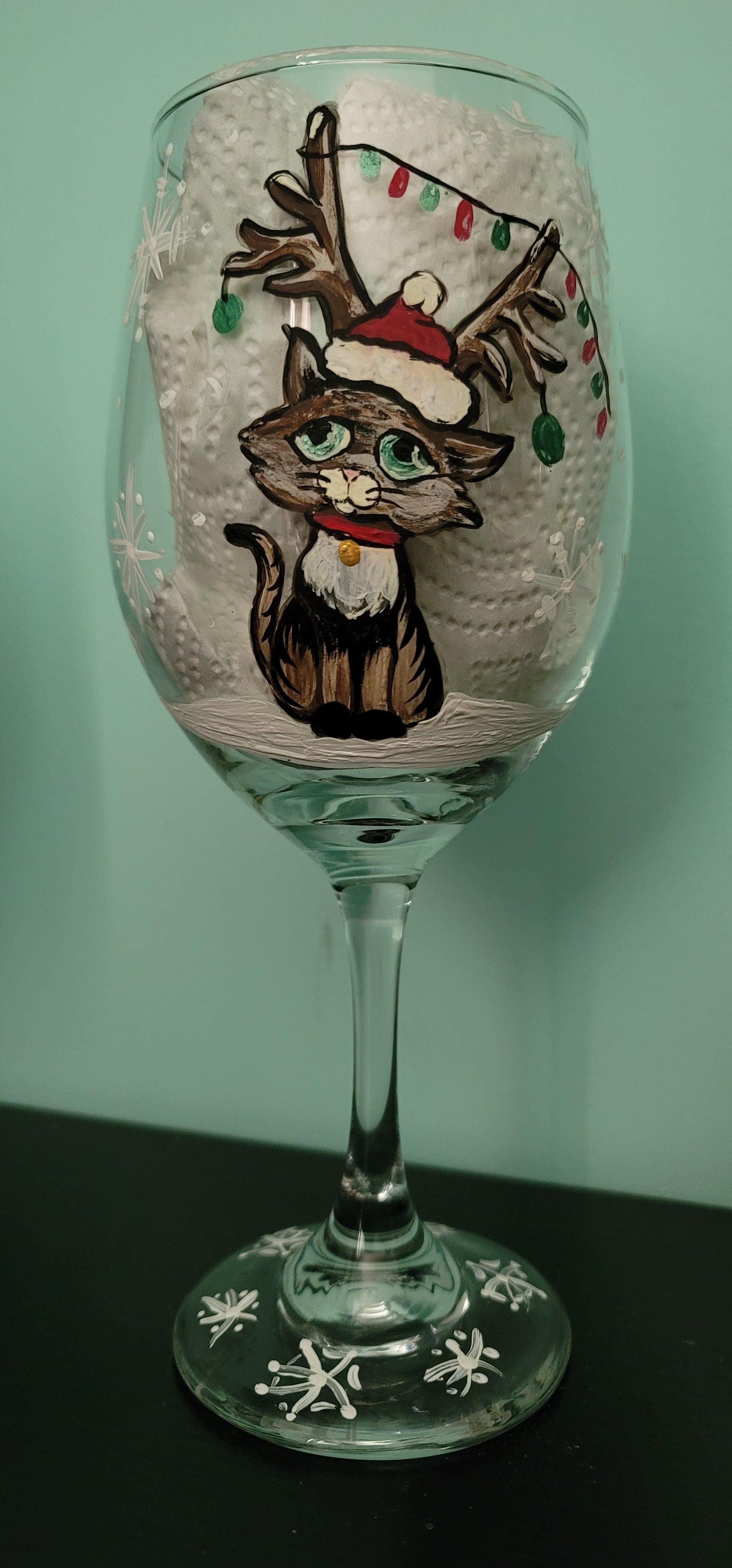 Christmas kitten with lights on stemmed wine glass.