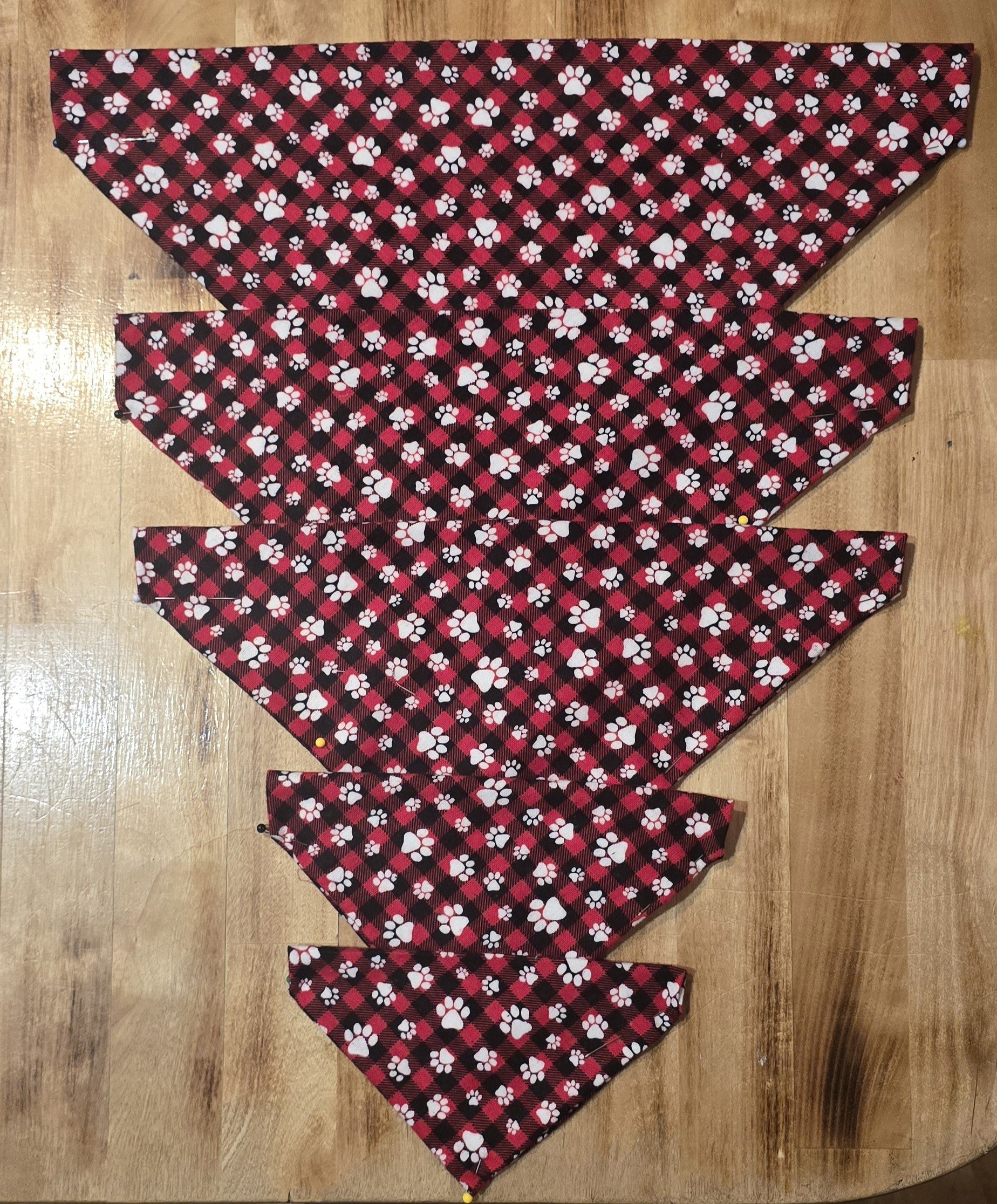 Red and black dog bandanas with white paw prints in multiple sizes.